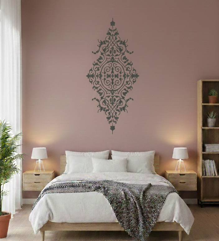 Decorative baroque wall stencil above a bed on a soft pink accent wall in a cozy bedroom