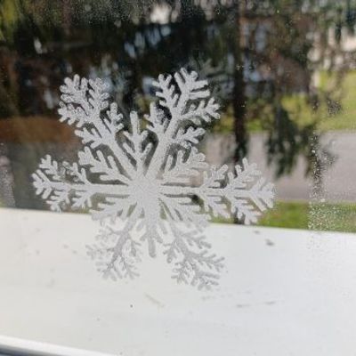 Large snowflake window decoration in white, creating a winter-themed display on glass.