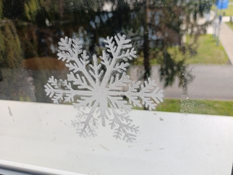 Large snowflake window decoration in white, creating a winter-themed display on glass.