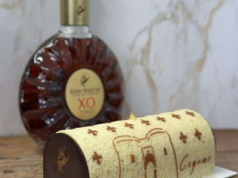 Cake decorated with custom Cognac stencil design next to Rémy Martin XO bottle