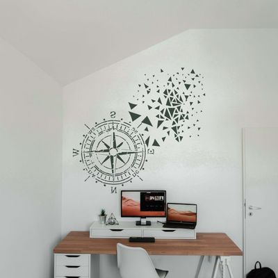 Modern home office wall decorated with a large compass stencil and abstract geometric pattern above a minimalist desk setup.