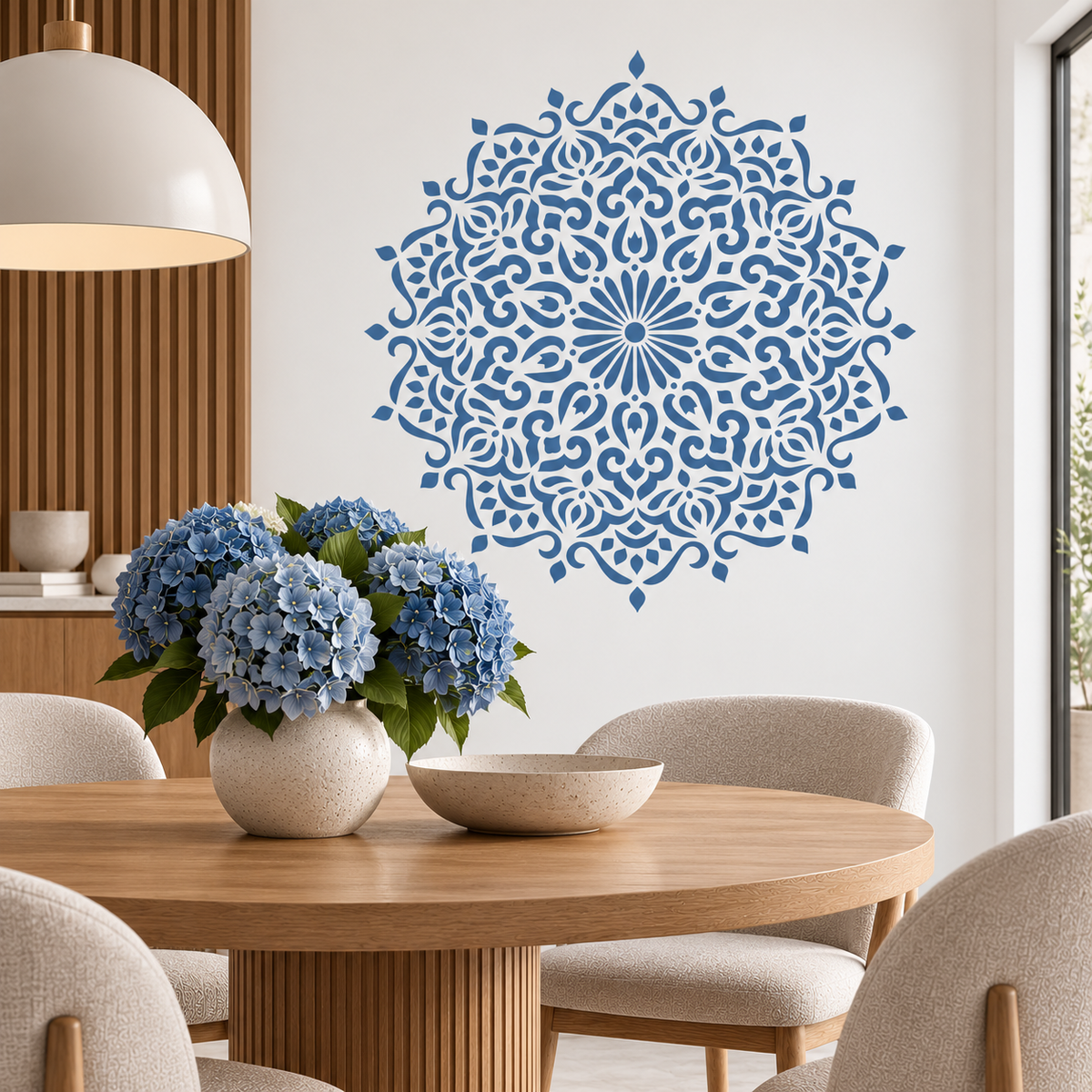 Decorative Mandala Stencil in blue on a white wall above a wooden dining table with blue hydrangeas.