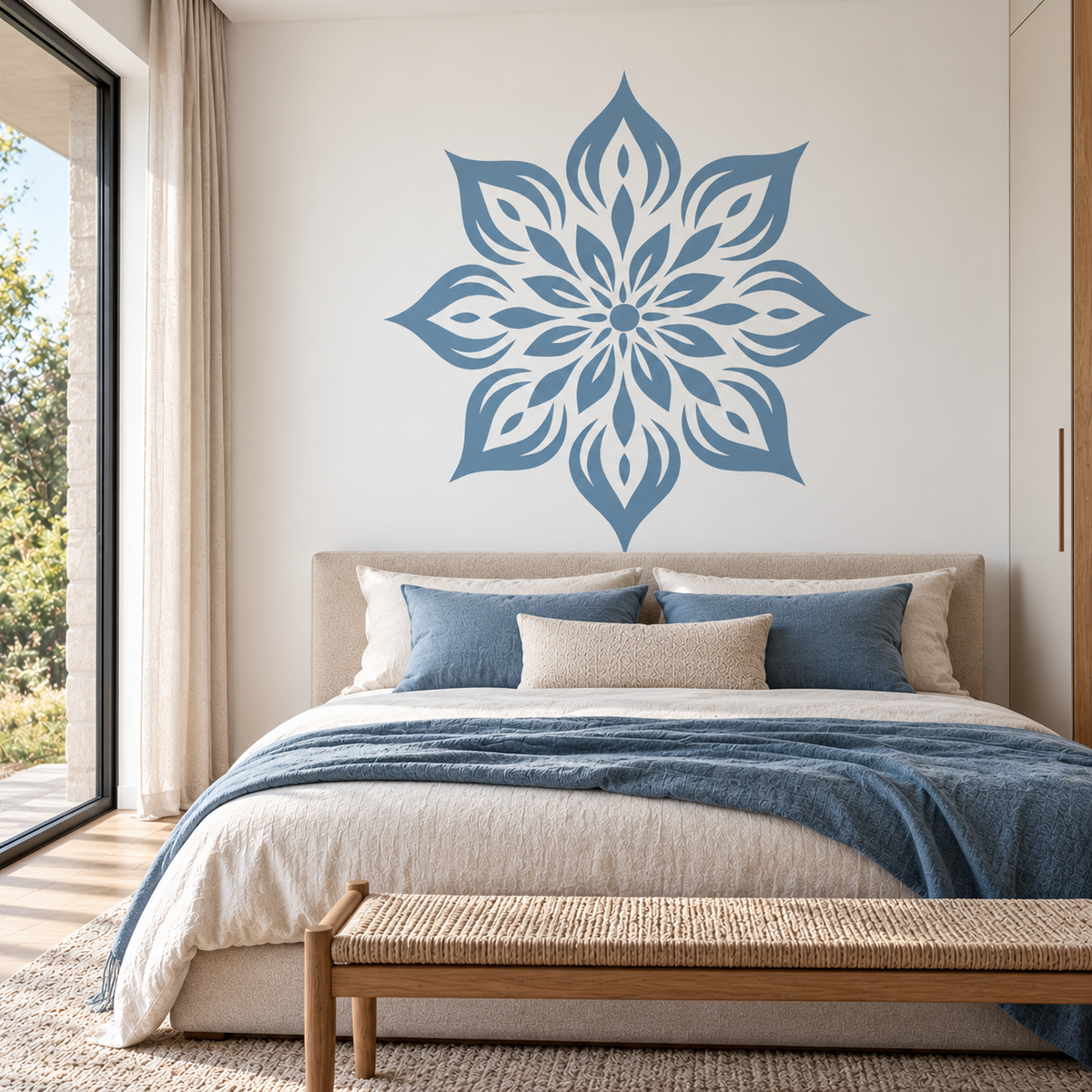 Dusty blue flower mandala wall stencil above a bed with matching blue bedding in a bright modern bedroom.