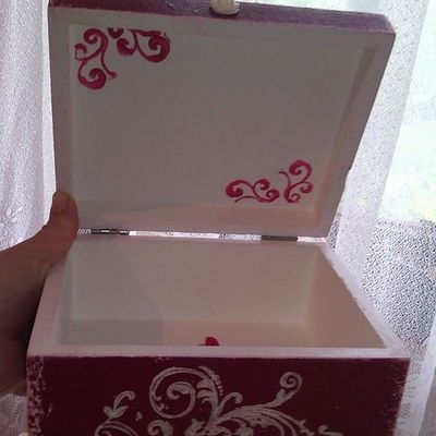 Hand-painted wooden box decorated with white stencil patterns and pink ornamental details inside the lid.