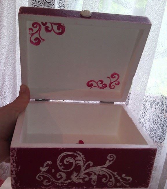 Hand-painted wooden box decorated with white stencil patterns and pink ornamental details inside the lid.