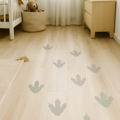 Gray dinosaur footprint stencil designs painted on a light wood nursery floor, creating a playful trail across the room.