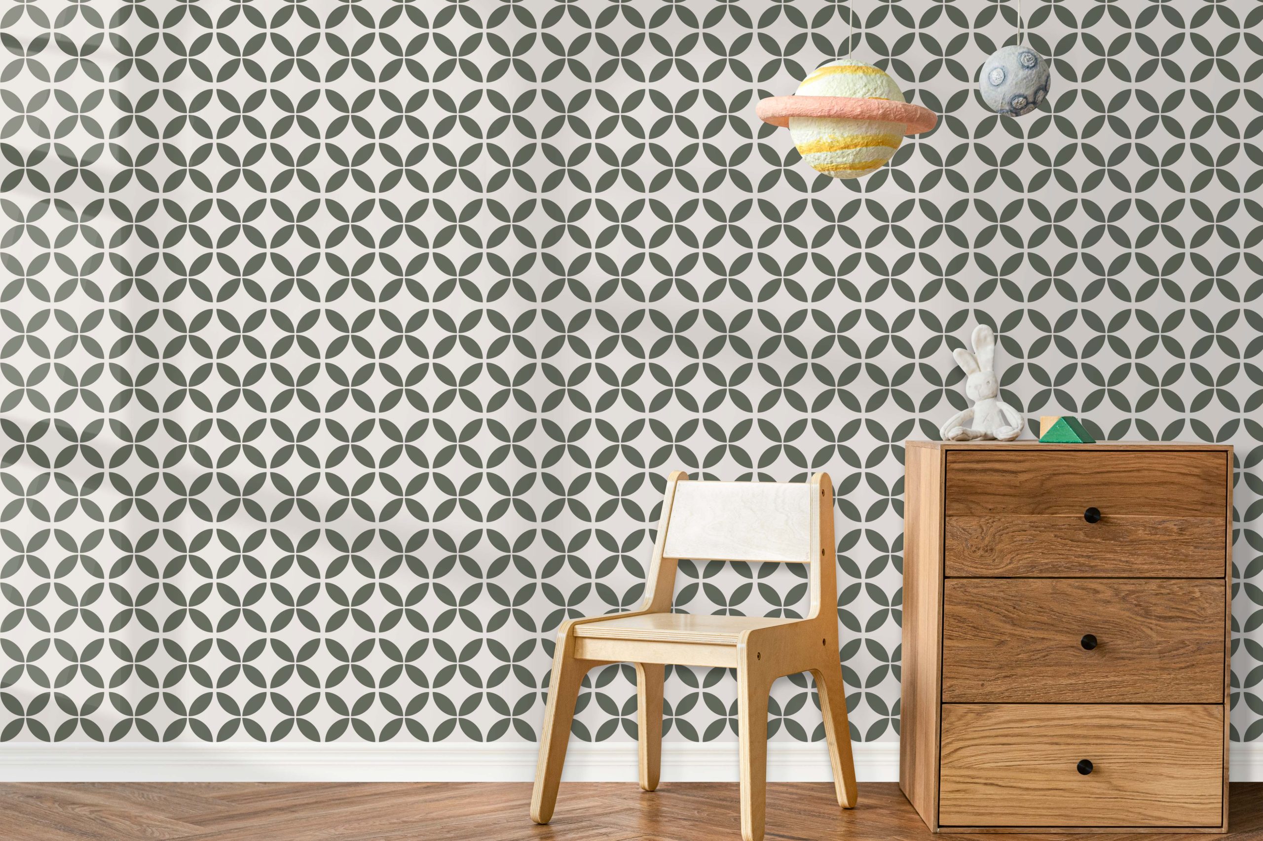 Interior wall decorated with a repeating Moroccan-style circular stencil pattern in soft green tones behind a wooden dresser and chair.