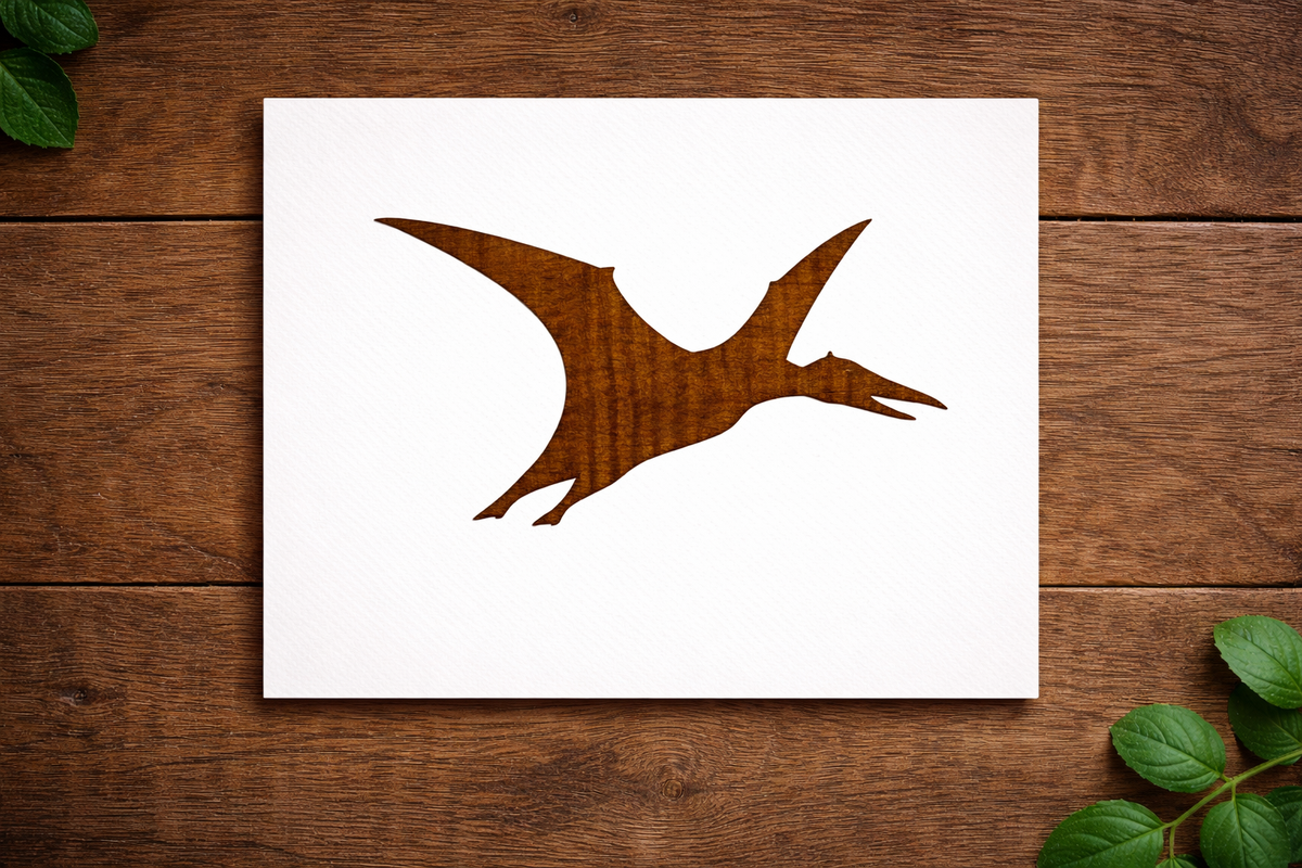 Reusable Pterodactyl dinosaur stencil made from 300 micron Mylar plastic placed on wooden background.