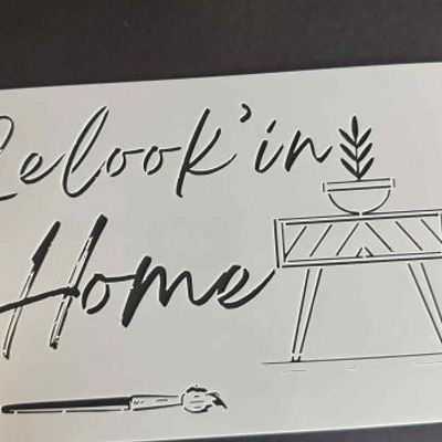 Decorative wall stencil with the handwritten phrase “Relookin’ Home” and minimalist furniture illustrations on a white sheet.