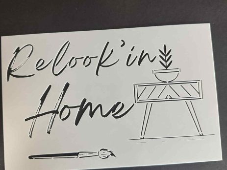 Decorative wall stencil with the handwritten phrase “Relookin’ Home” and minimalist furniture illustrations on a white sheet.