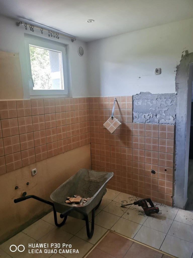 Removing old wall tiles during dining room renovation to prepare for modern wall stencils