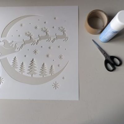 Santa sleigh stencil with crafting supplies arranged on a table, ready for creating a festive holiday decoration.