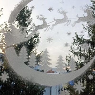 Santa sleigh stencil with reindeer and Christmas trees sprayed with artificial snow on a window