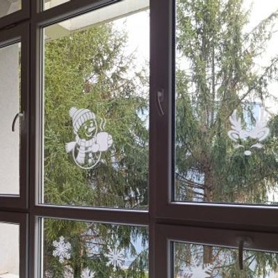 Snowman and reindeer window stencils creating a festive holiday scene with frosted white silhouettes on glass.