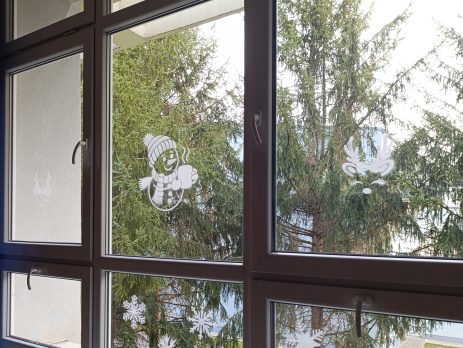 Snowman and reindeer window stencils creating a festive holiday scene with frosted white silhouettes on glass.