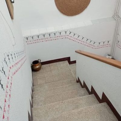 Staircase wall decorated with a repeating stencil border pattern featuring small human figures and geometric shapes along the stairwell.
