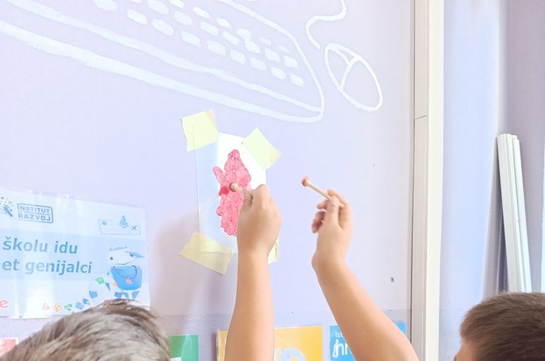 Students working together while applying a classroom wall stencil, collaborating on a creative decoration project.
